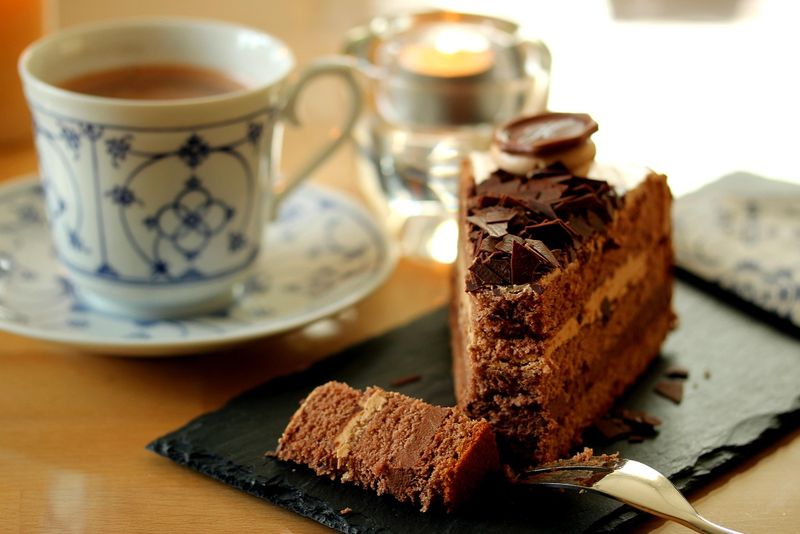 Stück Schokoladentorte neben Kaffeetasse auf Untertasse