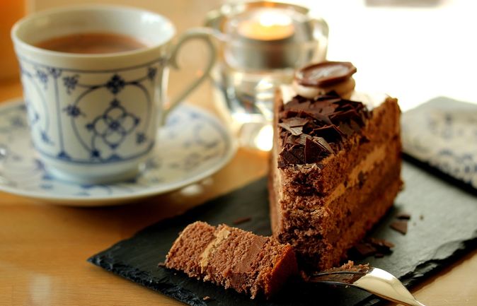 Stück Schokoladentorte neben Kaffeetasse auf Untertasse